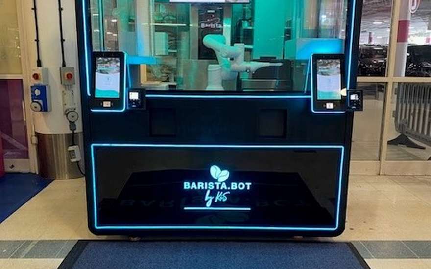 Barista.Bot robotic coffee kiosk at Weston Favell Shopping Centre, Northampton, with a lit sign and branded floor mat